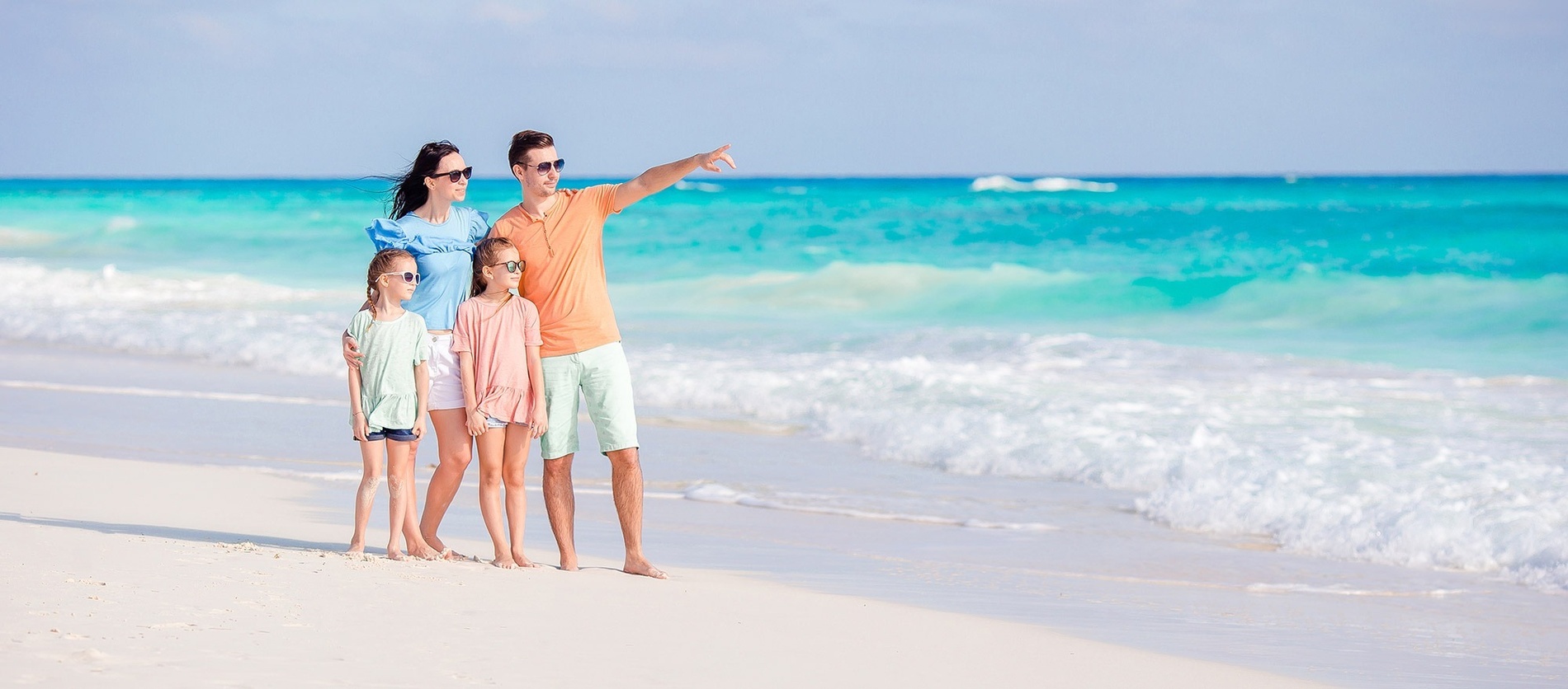 una familia se para en la playa mirando el océano