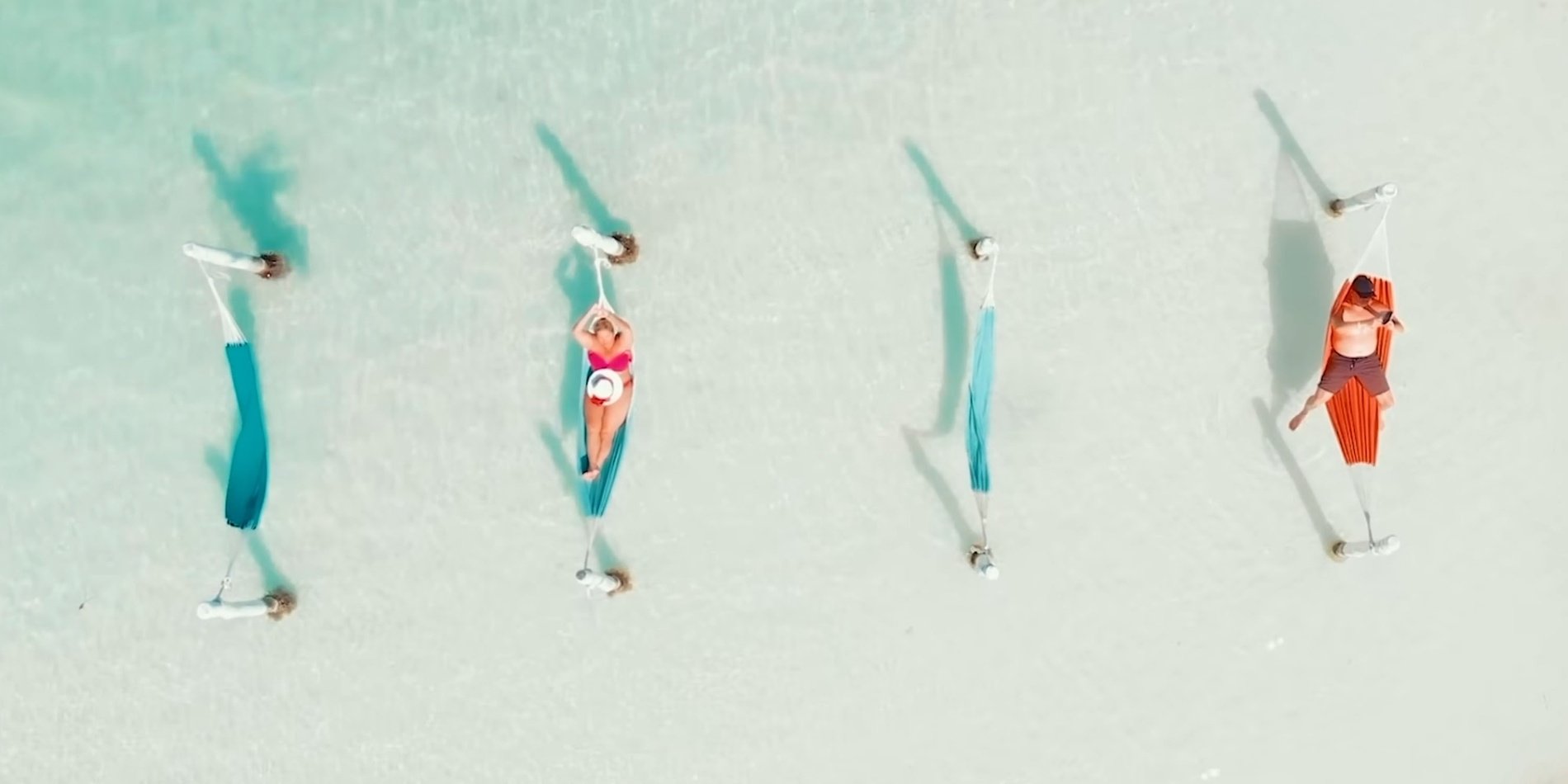 an aerial view of people laying in hammocks on the beach