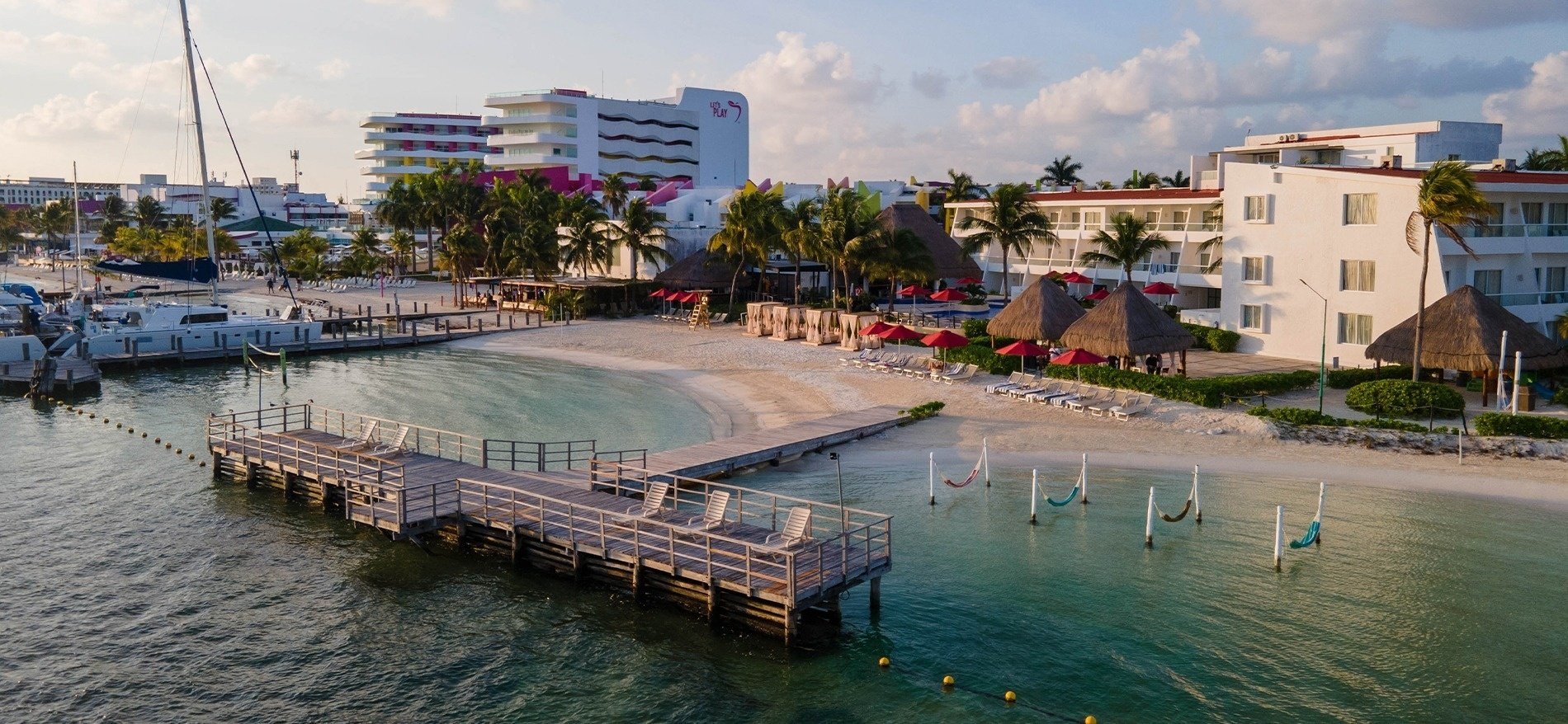 un muelle en la playa con hamacas y un hotel en el fondo