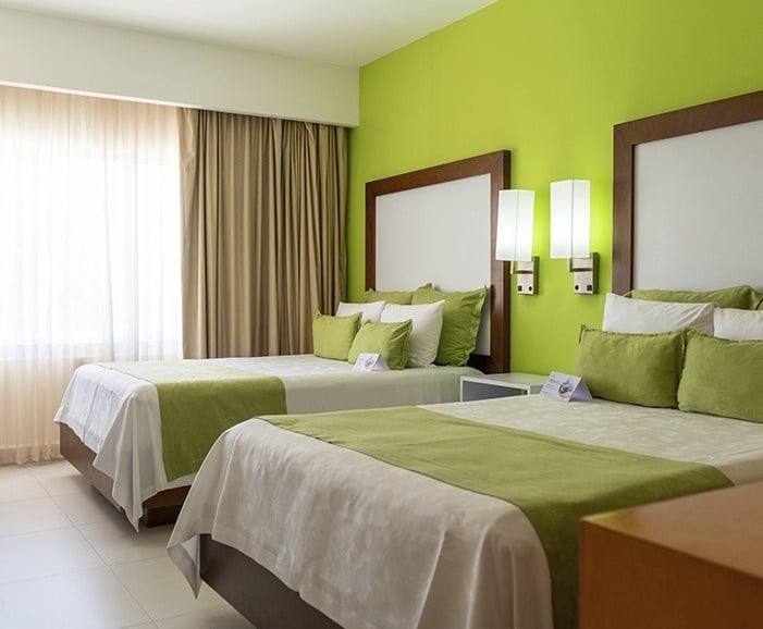 a hotel room with two beds and green walls