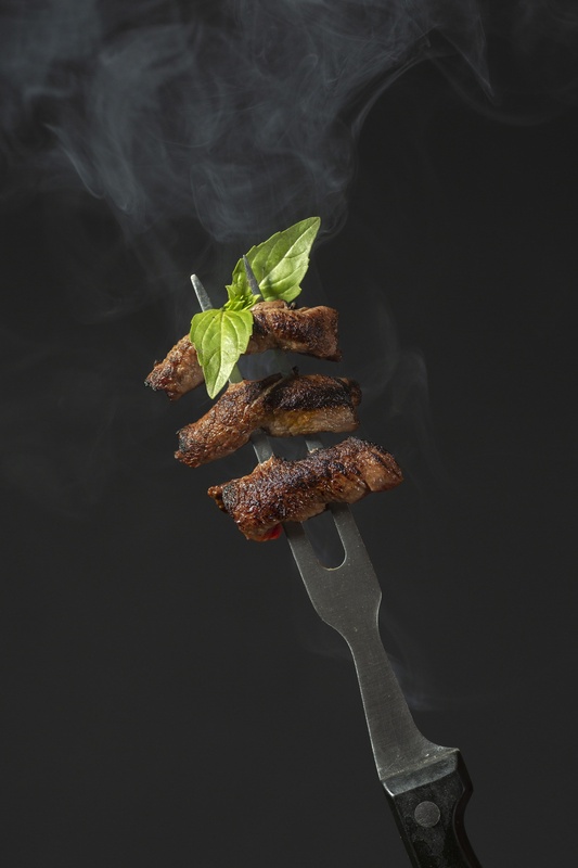 grilled meat on a fork with smoke coming out of it