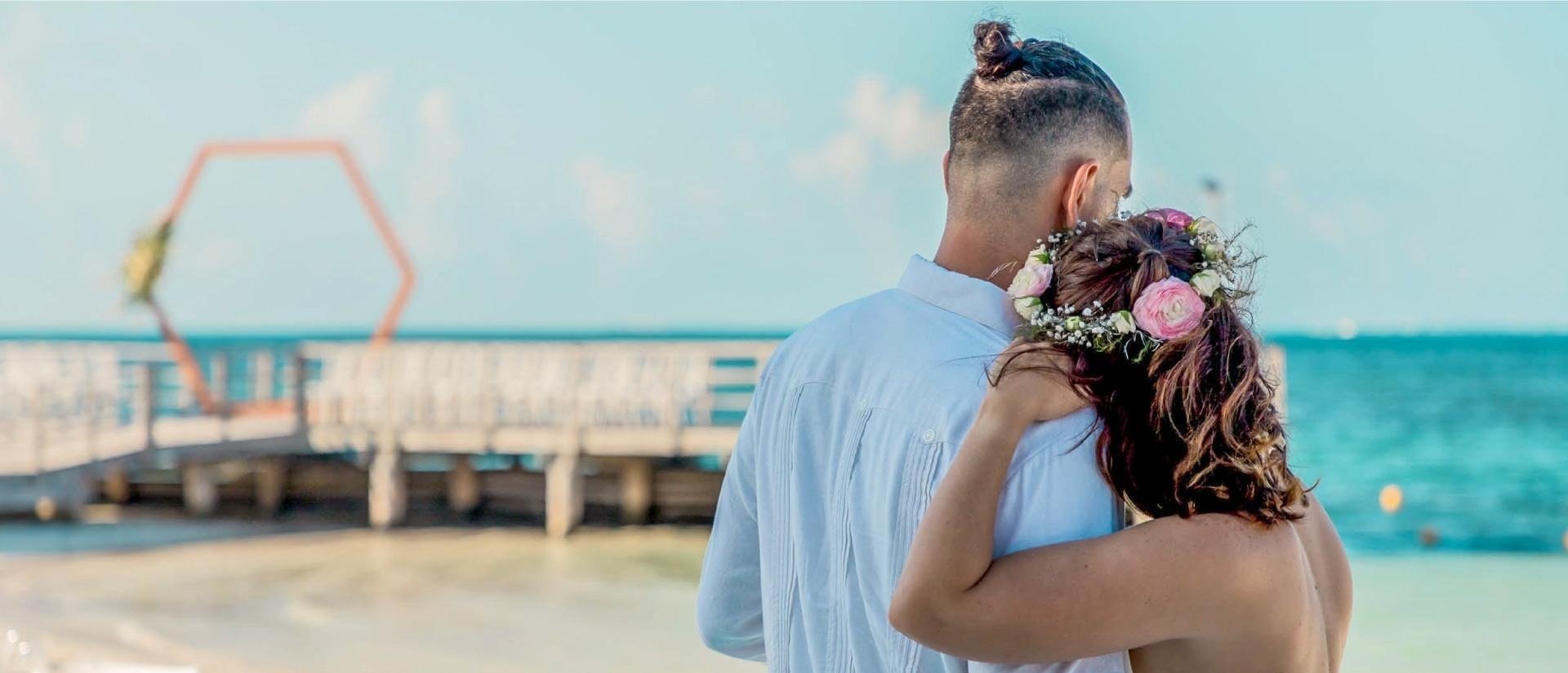 a man and a woman standing on a beach with flowers in their hair