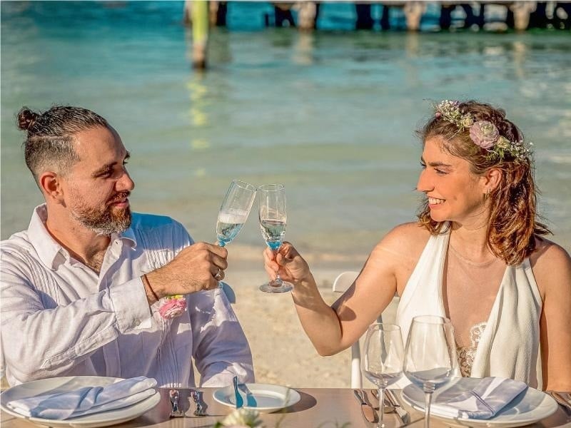 a man and woman toasting with champagne glasses on the beach