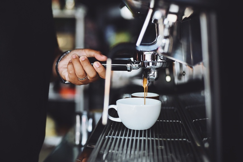 a person is pouring coffee into a white cup