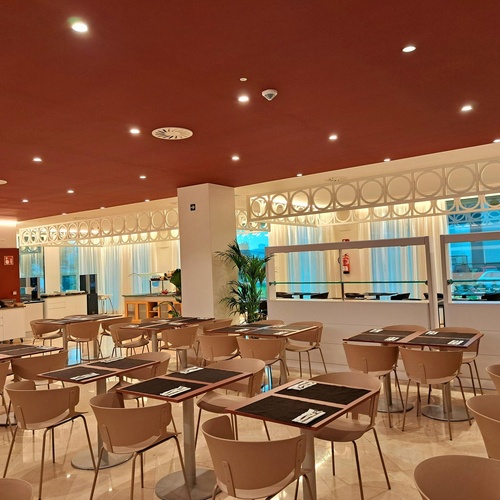 a restaurant with tables and chairs and a red ceiling