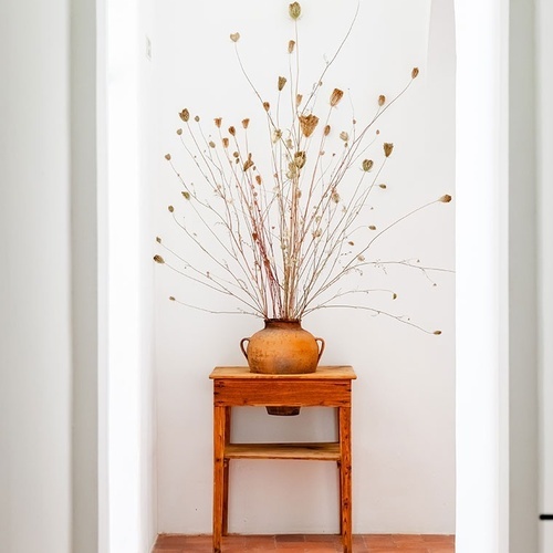 un jarrón con flores secas sobre una mesa de madera
