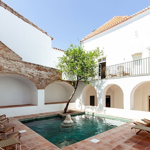 una piscina rodeada de sillas y un árbol en un patio