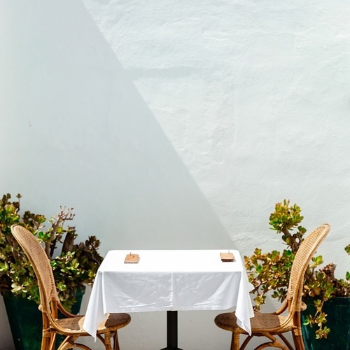 uma mesa com uma toalha branca e duas cadeiras de vime