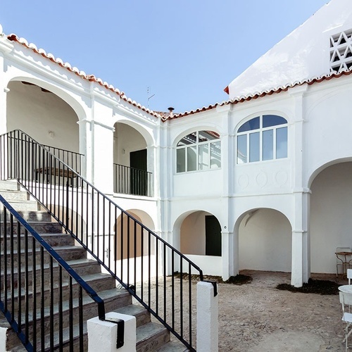 un edificio blanco con escaleras y sillas en el patio