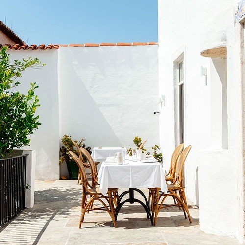 una mesa y sillas en un patio frente a una casa blanca