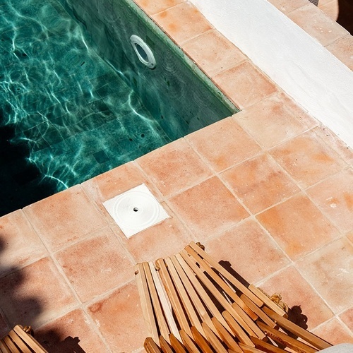 dos tumbonas de madera están junto a una piscina