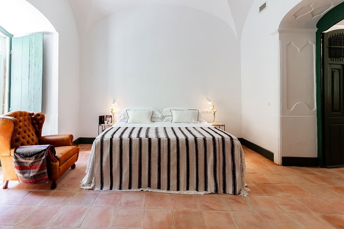 a bedroom with a striped bedspread and a chair