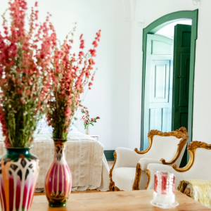 two vases of flowers sit on a table in front of a bedroom