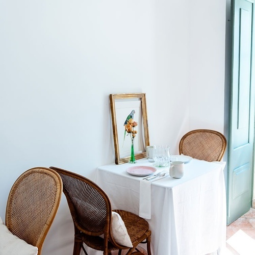 una mesa y sillas en una habitación con una pintura de un loro en el marco