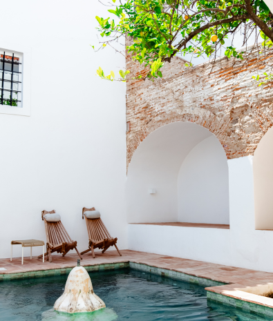 duas cadeiras de madeira estão ao lado de uma piscina