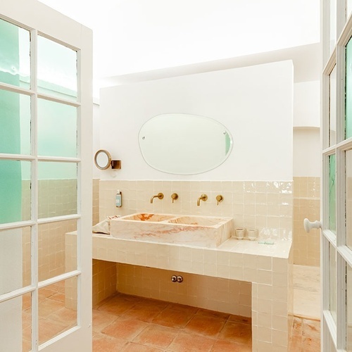 un baño con dos lavabos y un espejo redondo