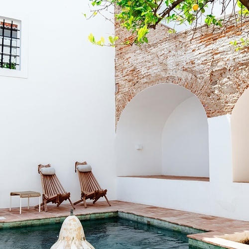 uma piscina com duas cadeiras de madeira ao lado dela