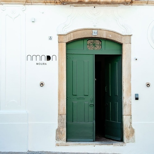 un edificio blanco con una puerta verde y la palabra moura en la pared