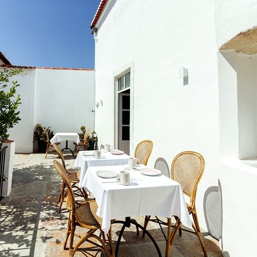 un patio con mesas y sillas y una pared blanca