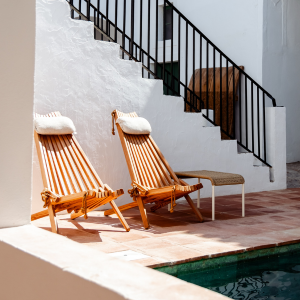 duas cadeiras de madeira estão ao lado de uma piscina