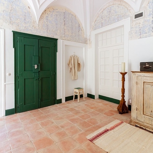 un pasillo con una puerta verde y un armario blanco