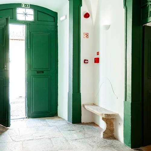un pasillo con una puerta verde y un banco