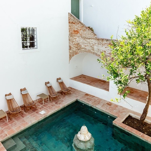 una piscina rodeada de sillas y un árbol