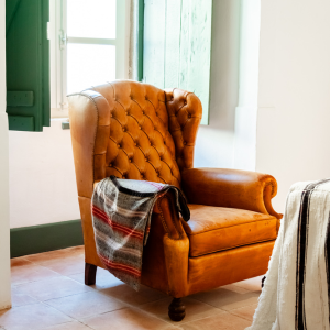 a brown leather chair with a plaid blanket on it