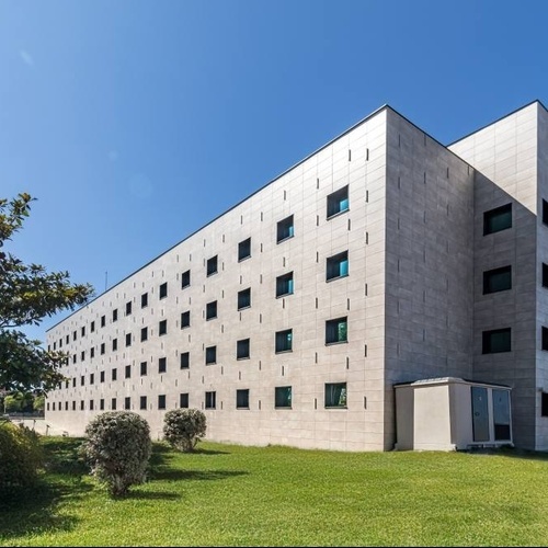 un gran edificio blanco con muchas ventanas está rodeado de hierba y árboles