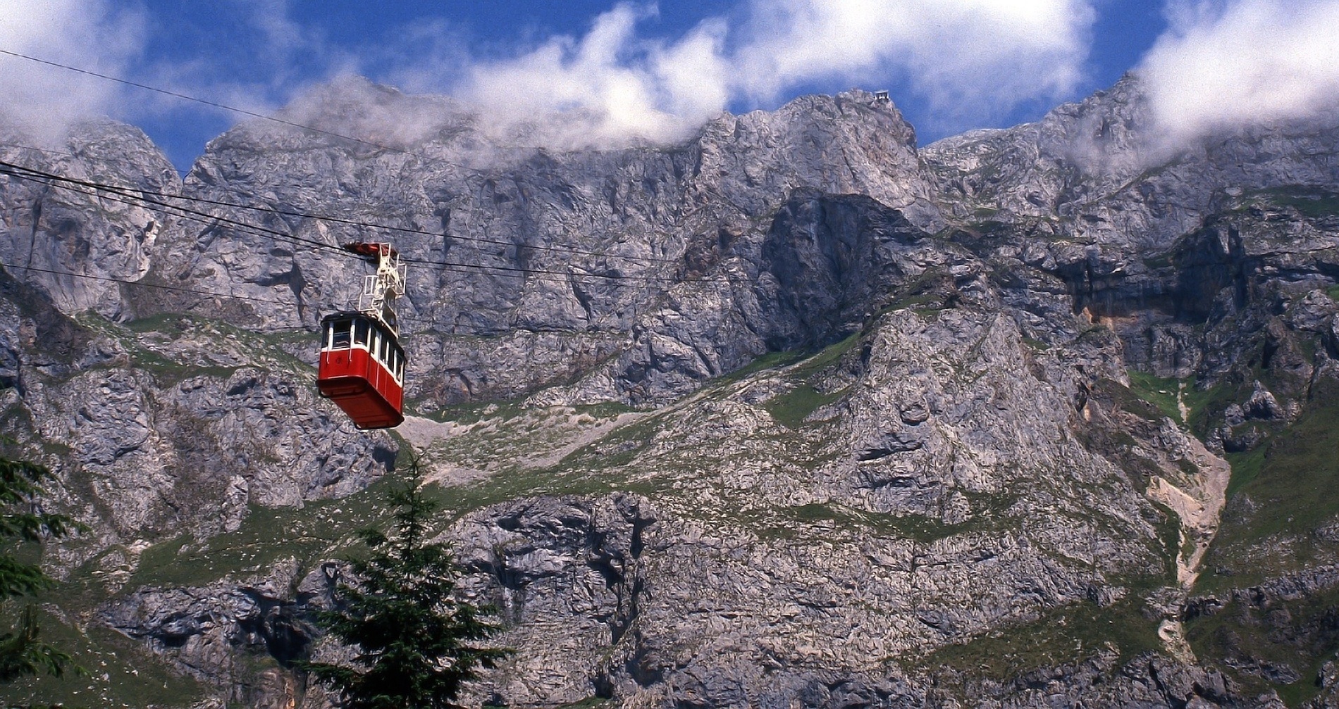 a red cable car is going up a mountain