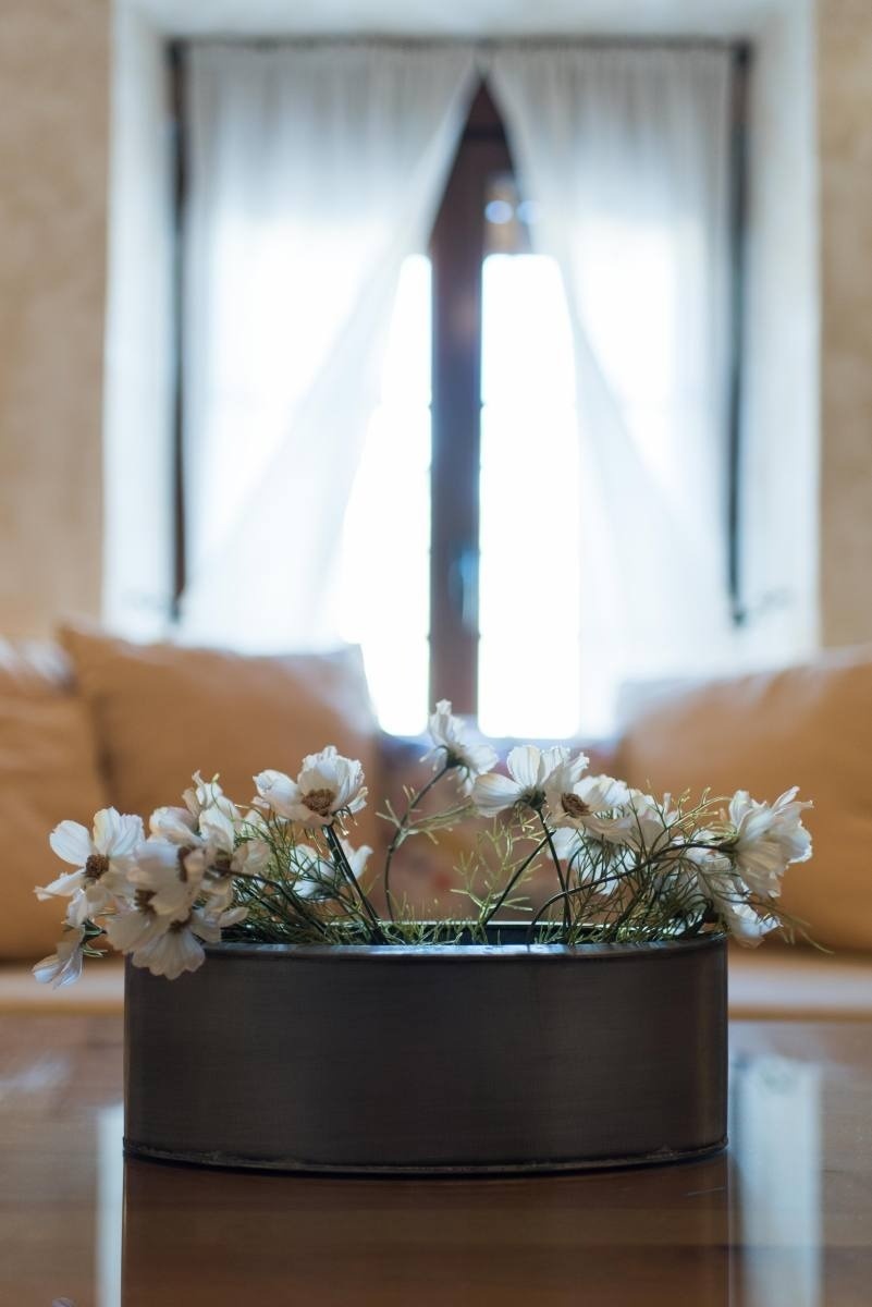 a vase filled with white flowers sits on a table in front of a window