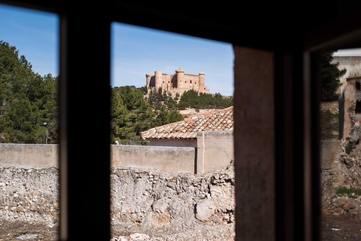 a view of a castle through a window with a stone wall in the foreground