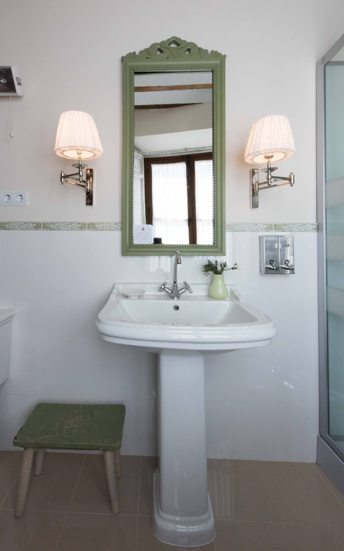 un baño con lavabo y espejo y un taburete verde