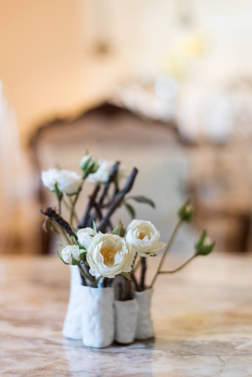 un jarrón lleno de flores blancas y ramas sobre una mesa