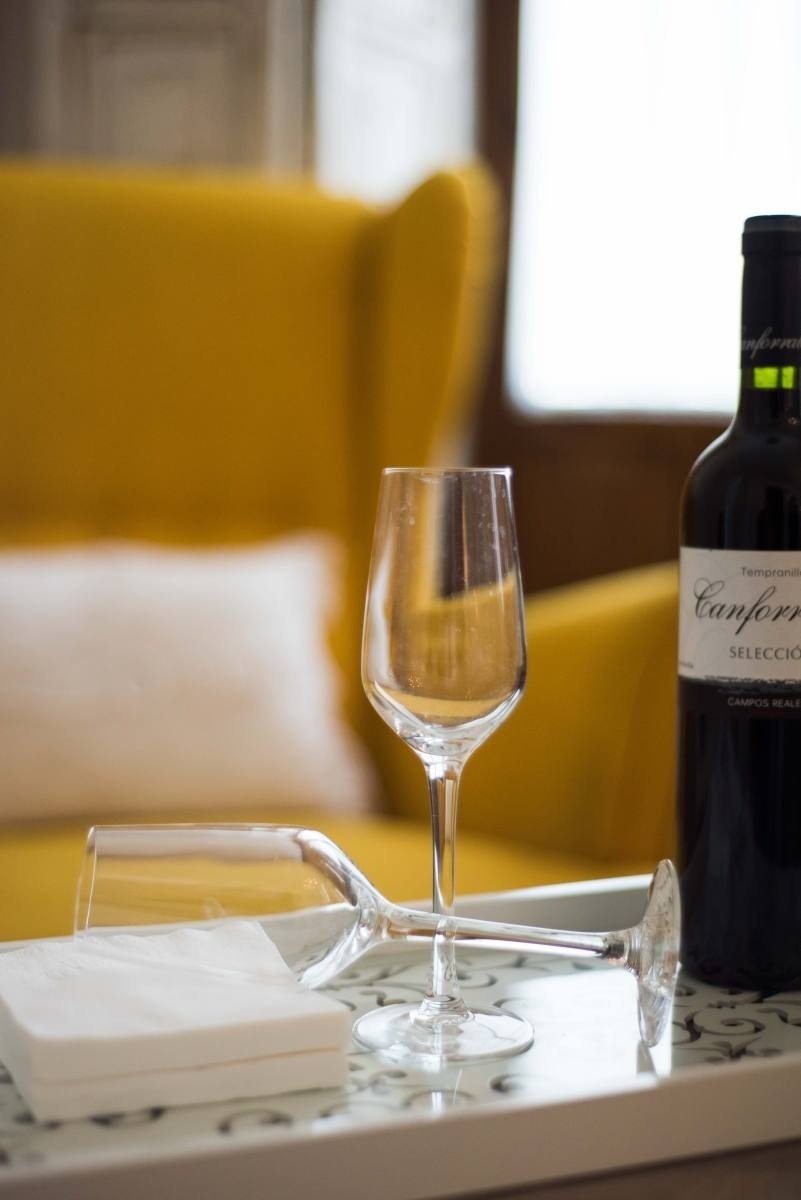 una botella de canfora se sienta en una bandeja junto a una copa de vino