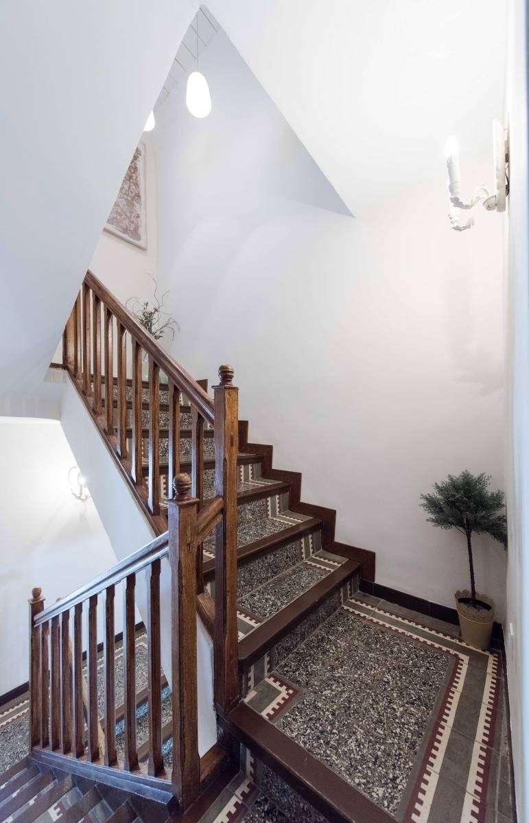 a staircase with a wooden railing and a tiled floor