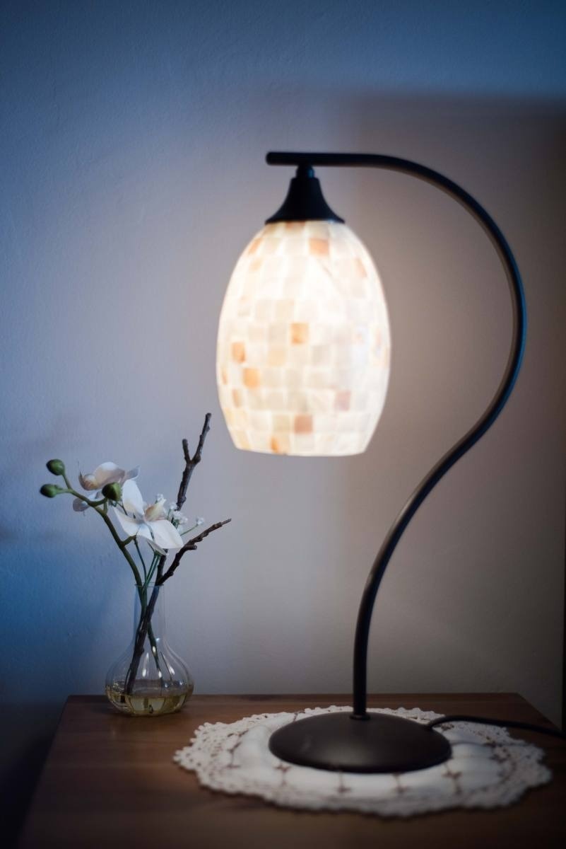 a lamp sitting on a table next to a vase of flowers