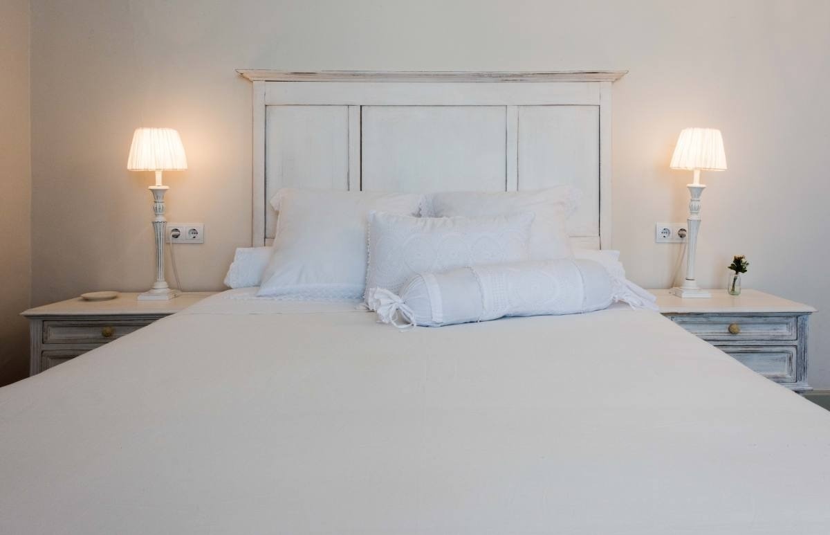 a bed with white sheets and pillows next to two lamps