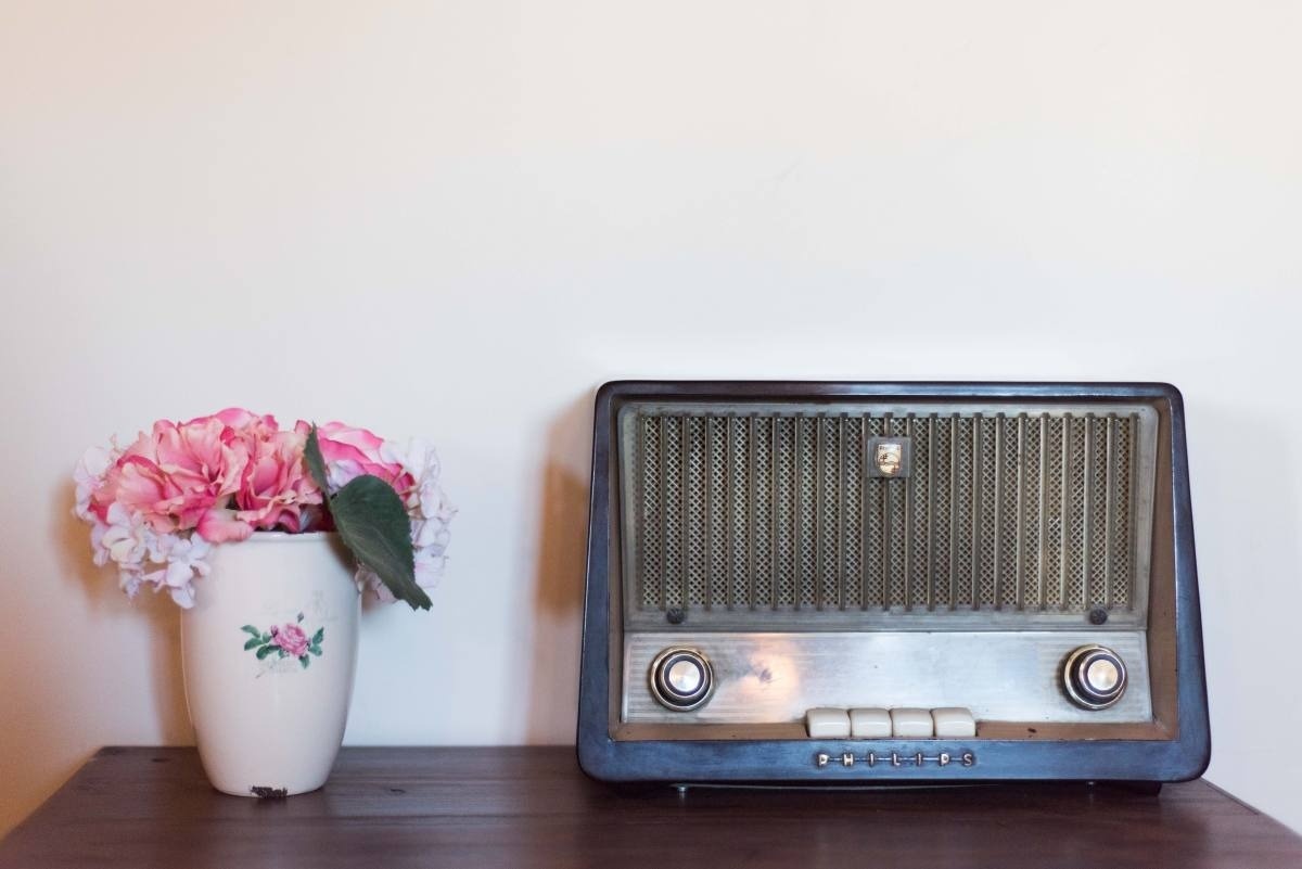 una radio antigua está sobre una mesa de madera junto a un jarrón de flores