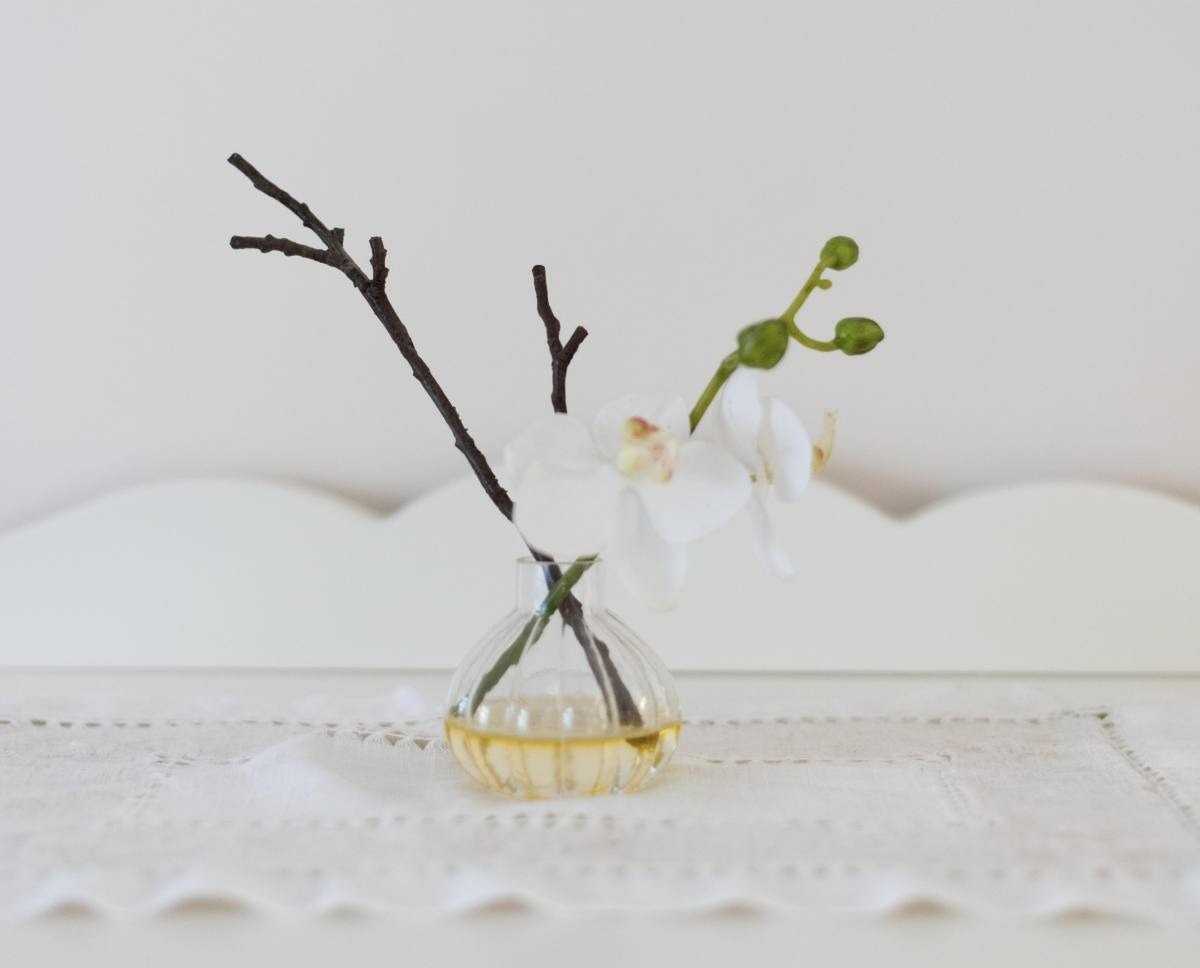un jarrón pequeño con flores y una rama en él