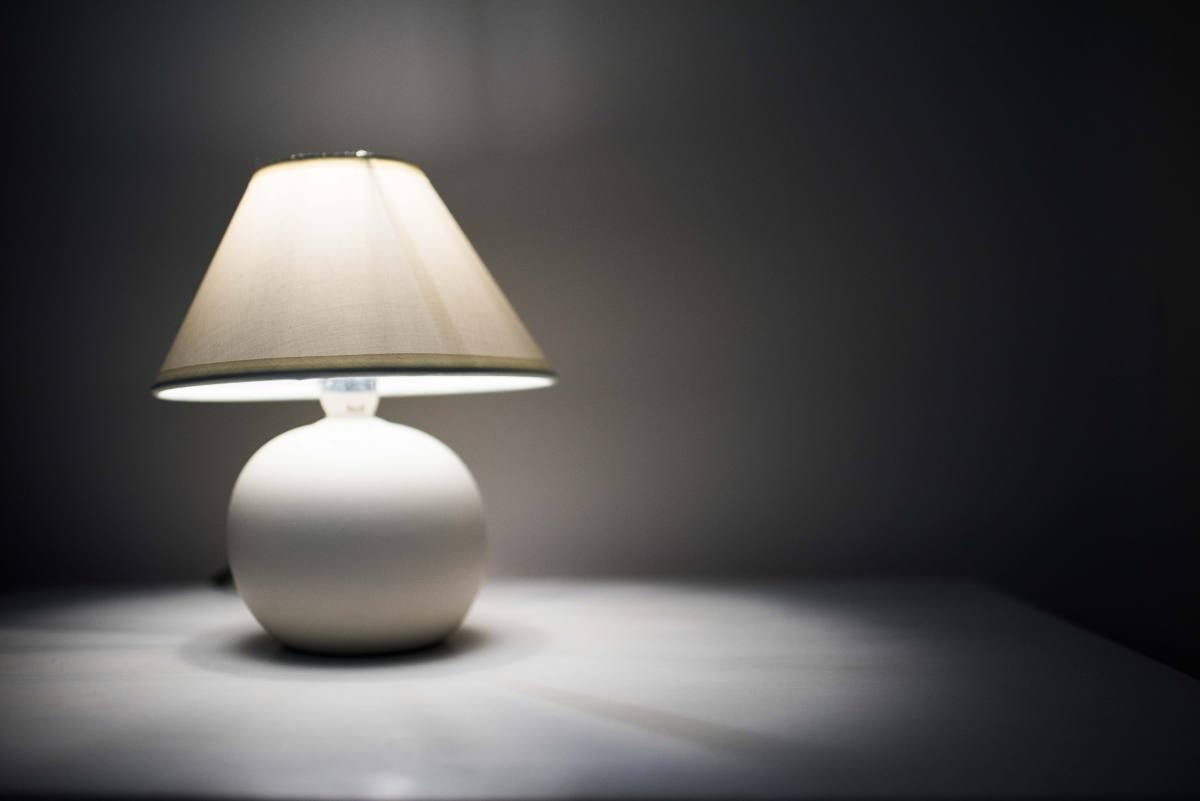 una lámpara blanca está encendida en una habitación oscura