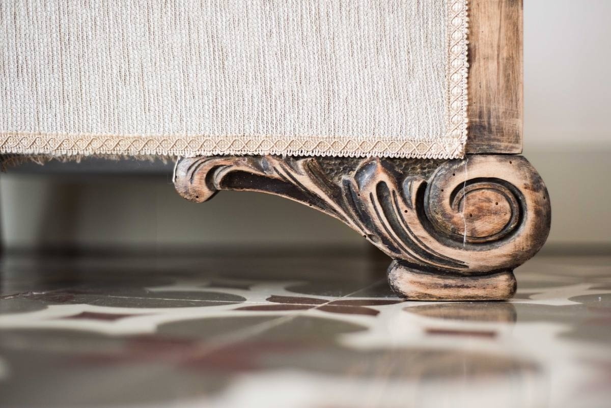 a carved wooden leg of a couch on a tiled floor