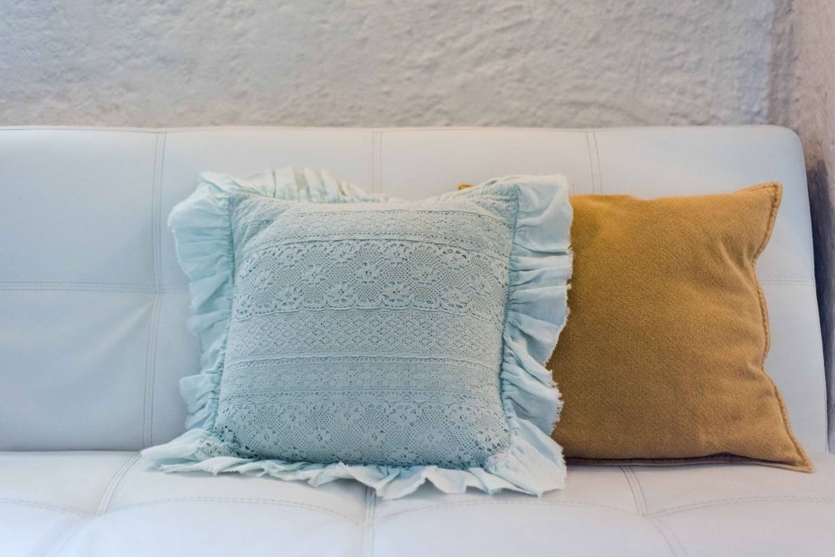 two pillows are sitting on a white leather couch