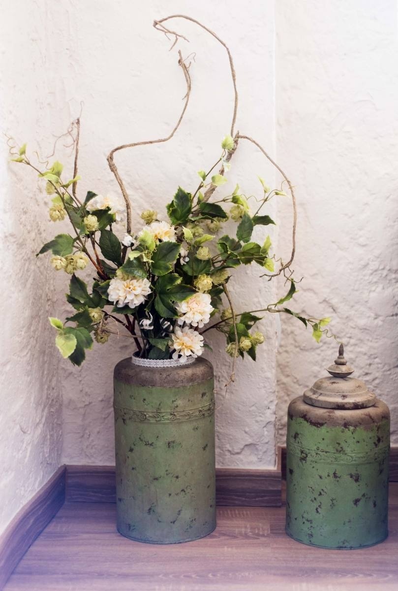 a green vase filled with white flowers sits next to a green jar