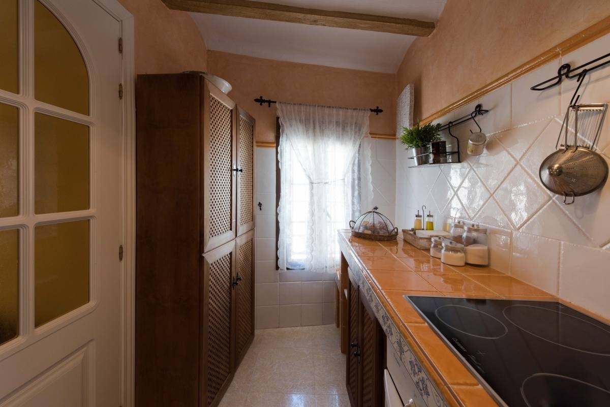 una cocina con una estufa de cerámica y gabinetes de madera
