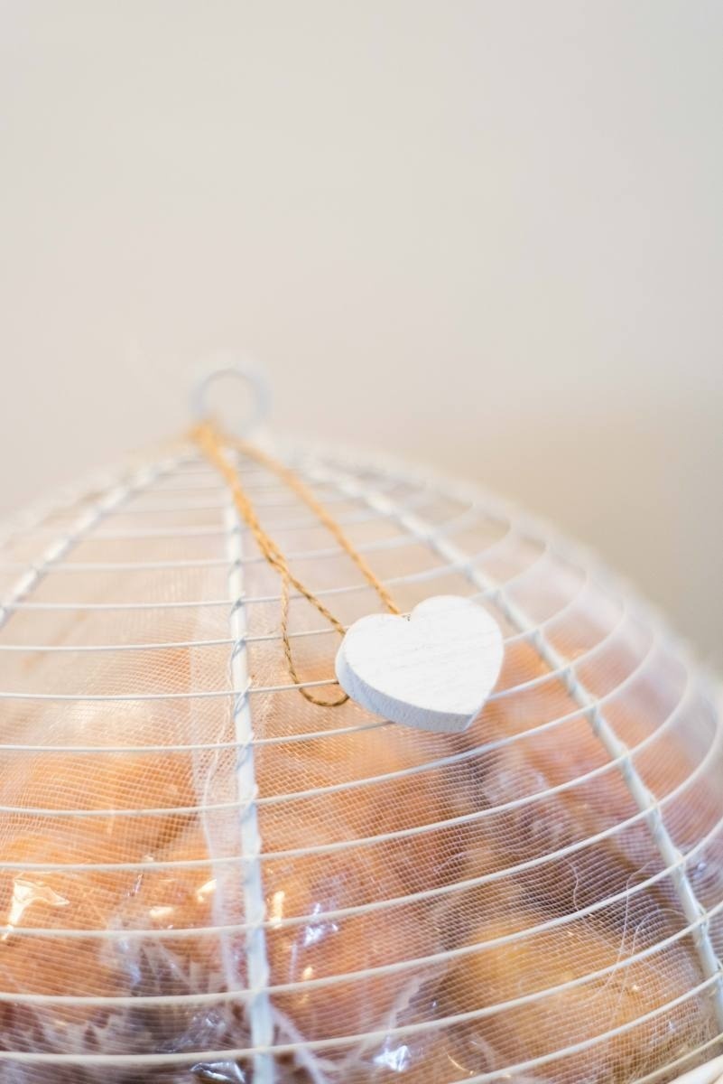 a white heart is hanging from a wire cage