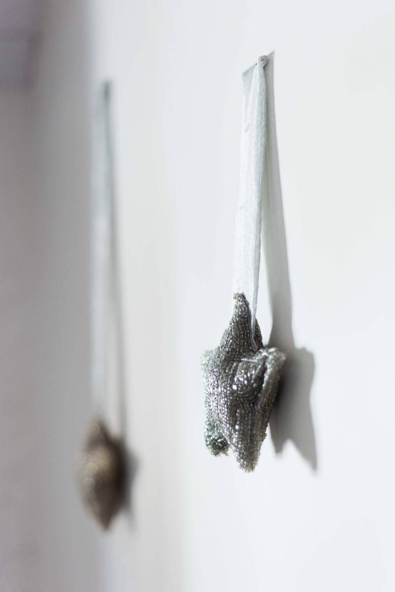 two silver star shaped ornaments hanging on a white wall