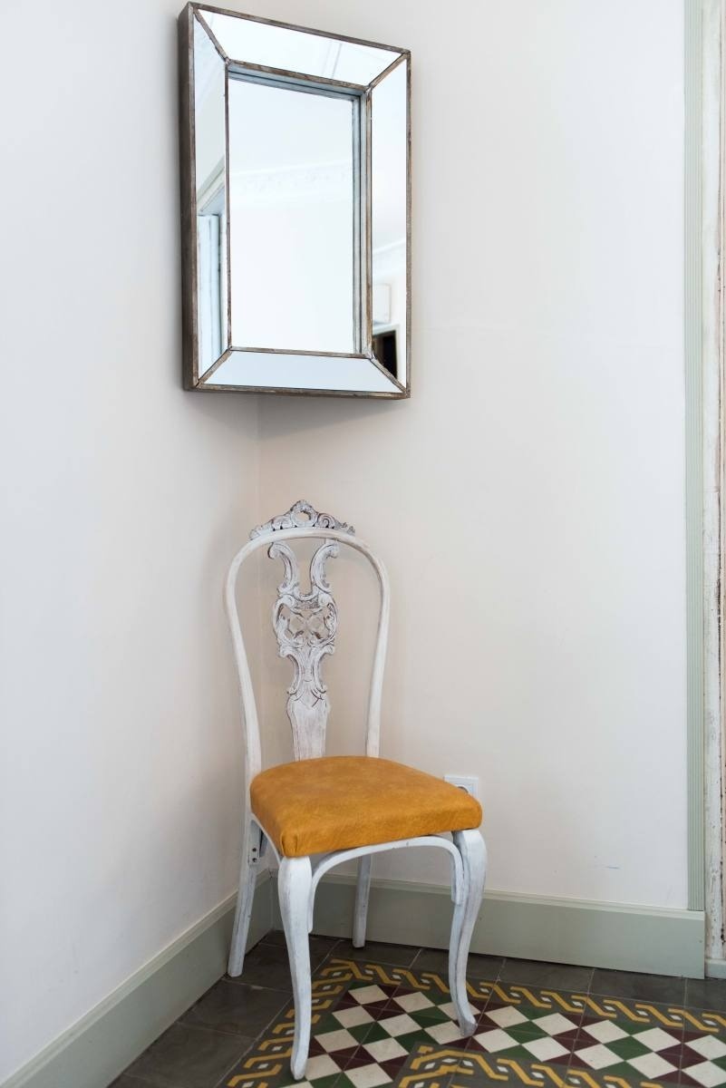 a chair sits in a corner next to a mirror