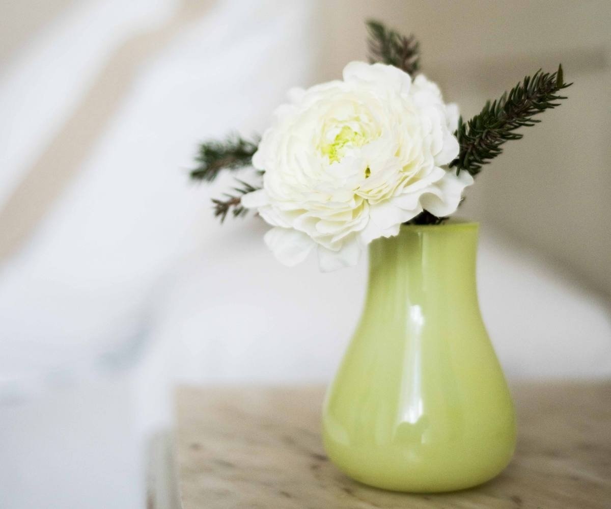 un jarrón verde con una flor blanca en él