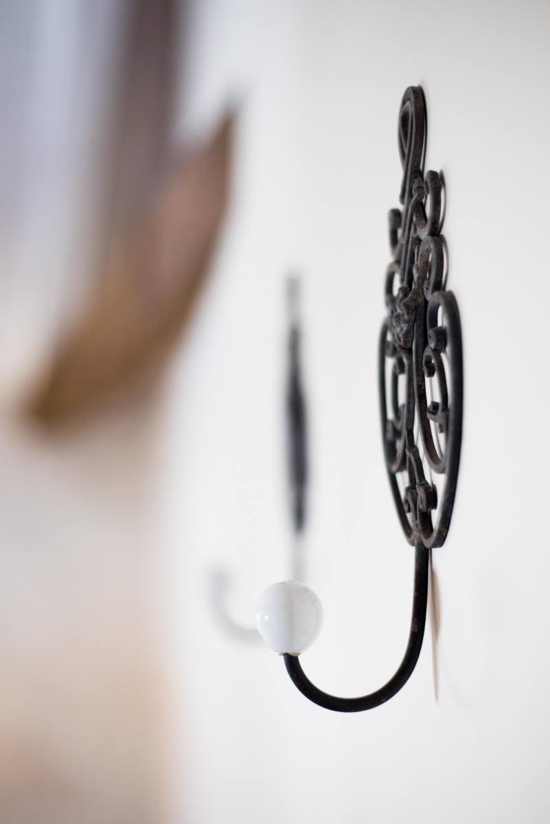 a black hook with a white ceramic knob is hanging on a white wall